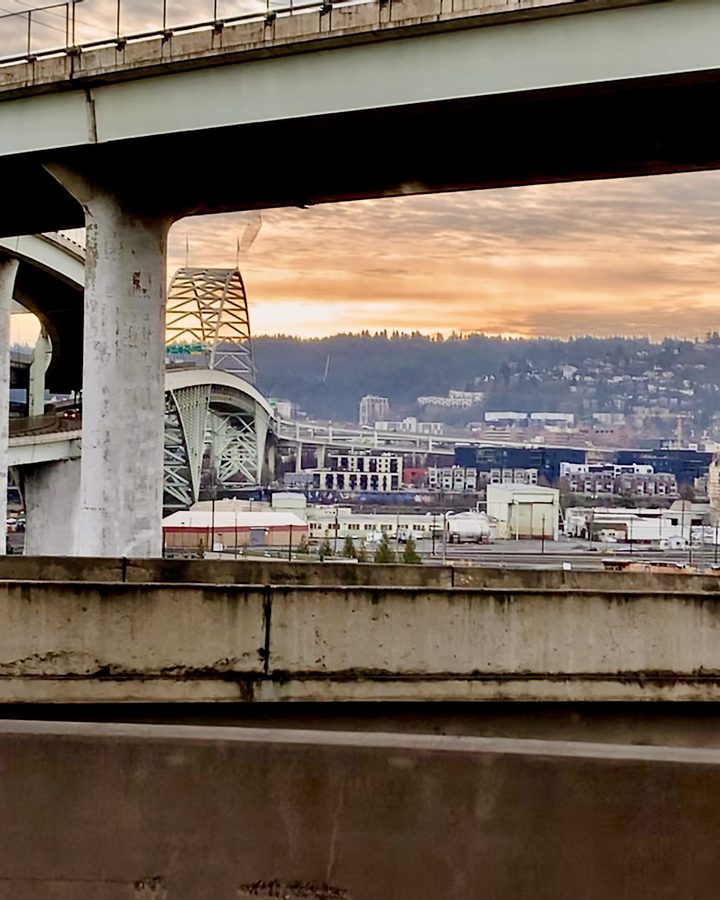 Portland's Fremont Bridge and the city at dusk, seen from under a freeway overpass